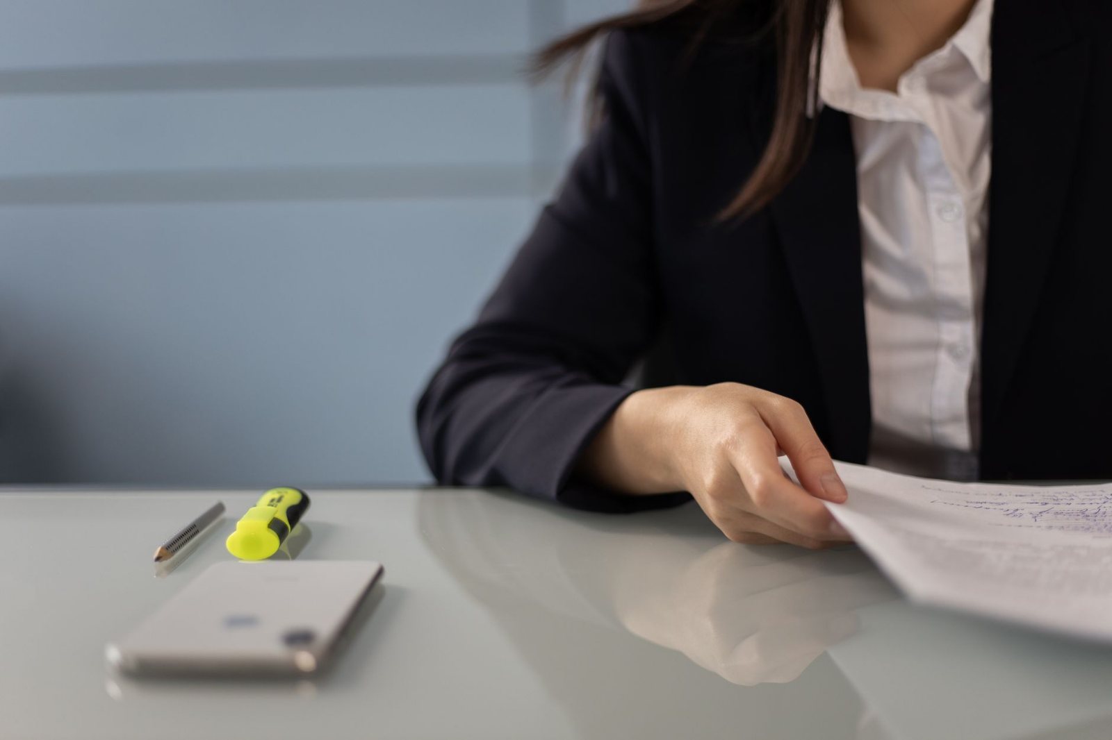 A coordinator's hand resting on a corded phone handset lifted off its cradle, over stapled freight paperwork
